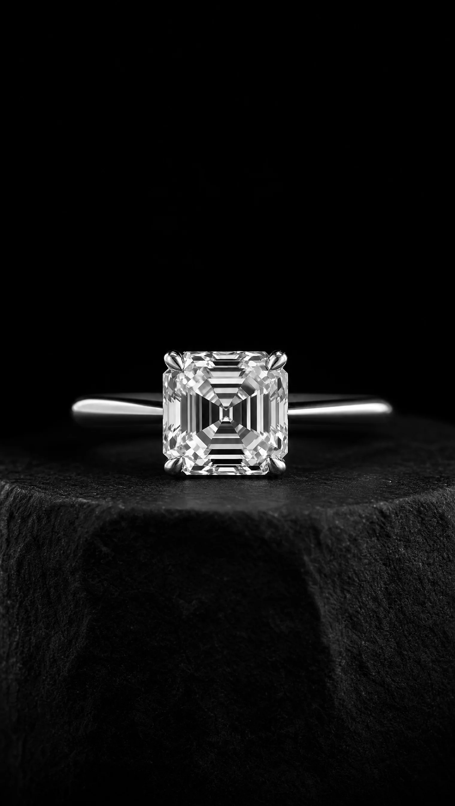 Antique asscher-cut diamond solitaire ring in platinum on a black stone pedestal