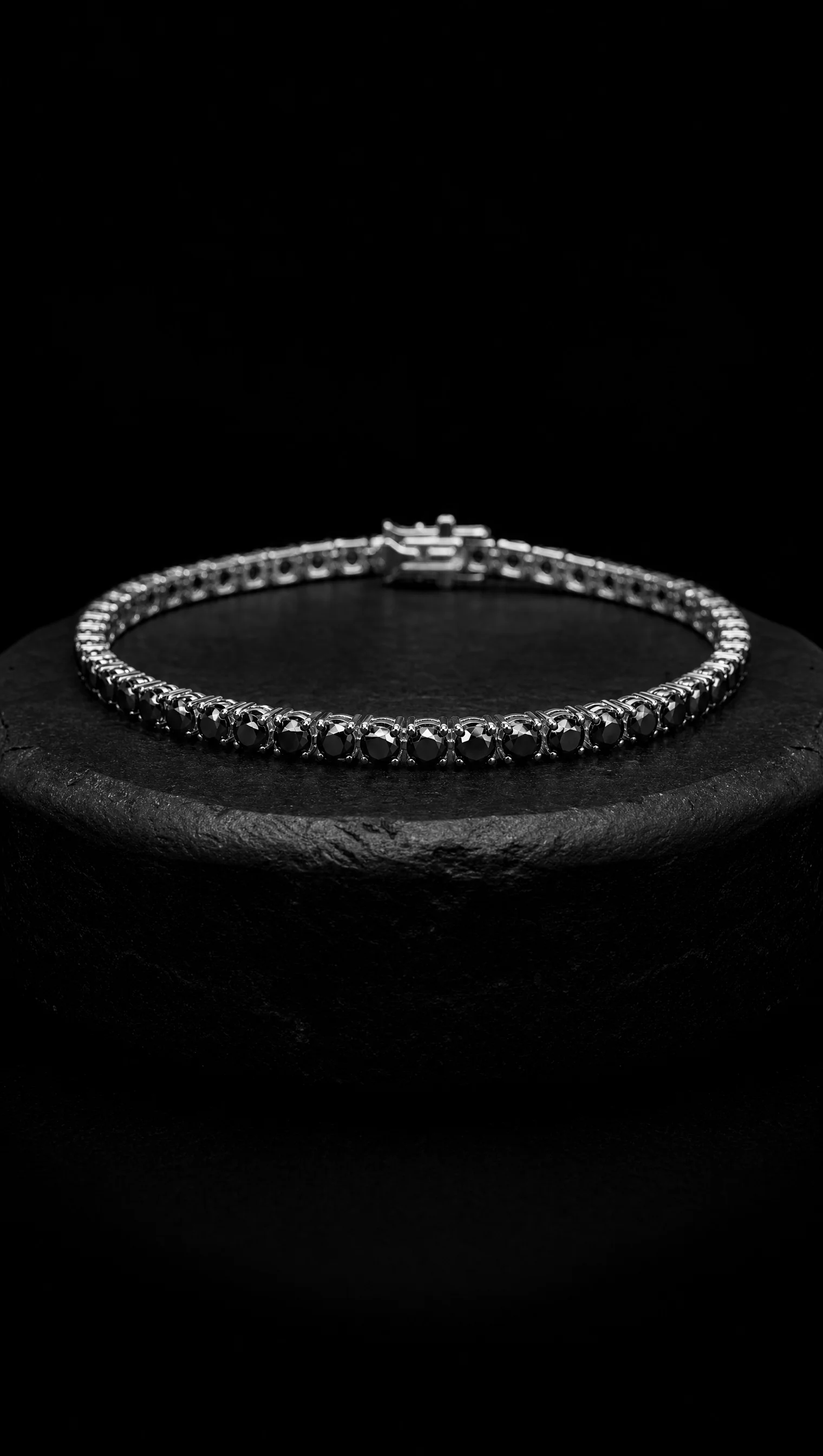 Black diamond line bracelet coiled on a black stone pedestal