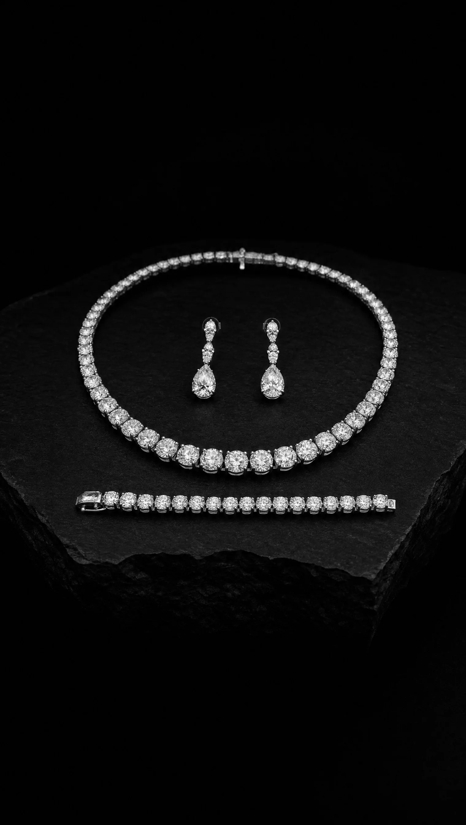 Matched parure of diamond rivière necklace, pendant earrings and line bracelet arranged together