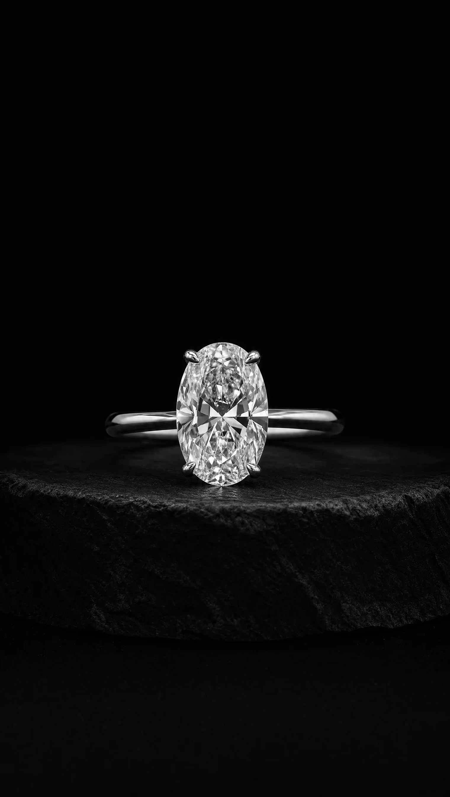 Oval diamond solitaire ring in platinum on a black stone pedestal