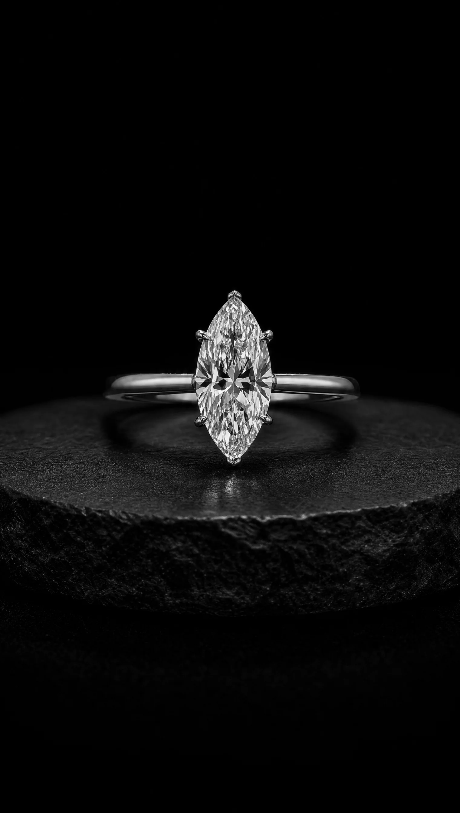 Marquise diamond solitaire ring in platinum on a black stone pedestal